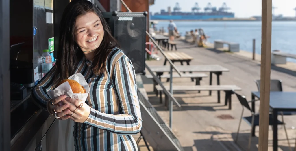 Kvinde med street food på en solrig kaj ved havnen
