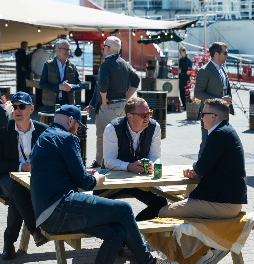 Gæster spiser ved bænke på havnen til et firmaarrangement