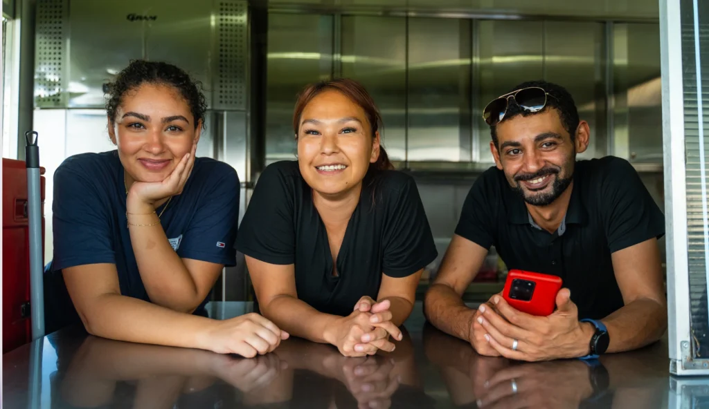 Tre smilende medarbejdere i en foodtruck